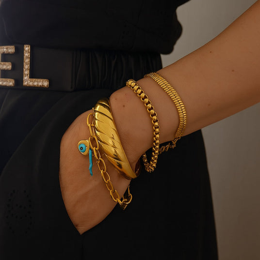 Close-up of a person's arm wearing gold bracelets with a blurred background